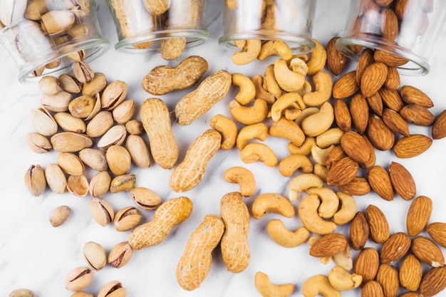 Foto vista de arriba de la comida de nueces derramada del frasco en la superficie de mármol