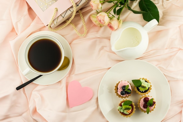 Vista desde arriba para un delicioso desayuno en la cama el día de San Valentín. taza de café, regalo, flores.