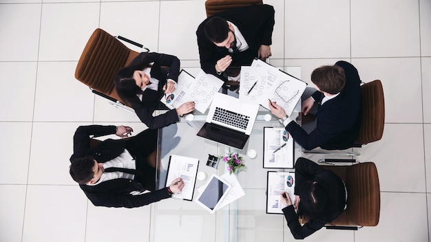 Vista desde arriba: el director ejecutivo y el equipo empresarial en una reunión de trabajo en una oficina moderna.