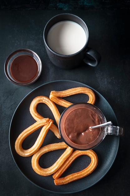 Vista desde arriba de una mesa de desayuno con leche con chocolate caliente y churros frescos