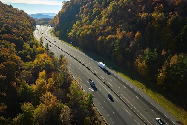 Vista desde arriba de la ruta de la autopista I40 en Carolina del Norte que conduce a Asheville a través de las montañas Apalaches con bosques de otoño amarillos y camiones y automóviles en movimiento rápido Concepto de transporte interestatal