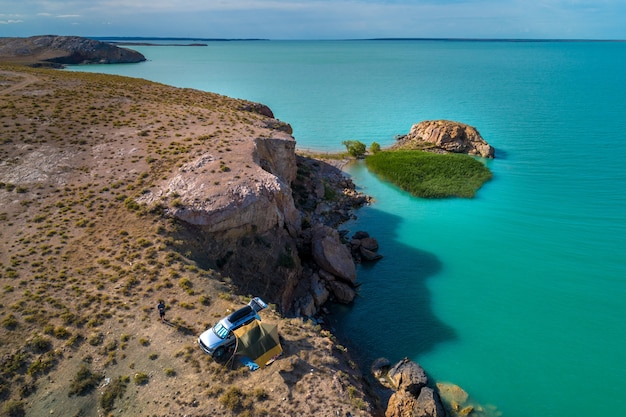 Vista desde arriba, vista desde el aire al mar esmeralda con la playa y turistas en coche