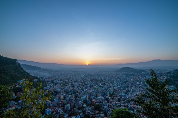 Una vista del atardecer de una ciudad con la puesta de sol detrás de ella