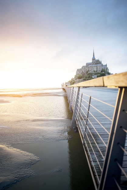 Vista del atardecer en la famosa abadía de Mont Saint Michel con puente durante la marea en Francia