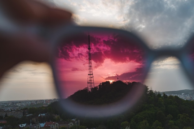 Vista del atardecer en gafas de sol sosteniendo a mano