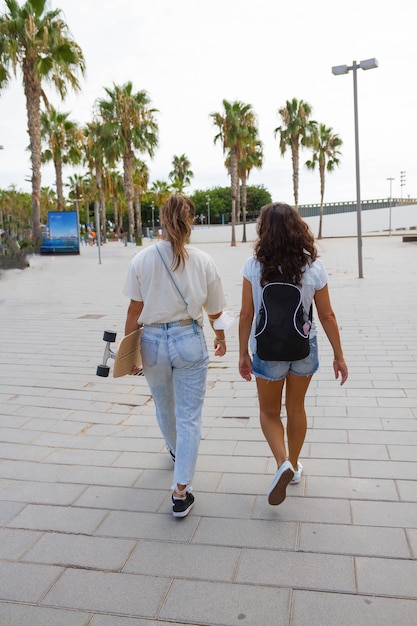 Foto vista desde atrás. dos jóvenes amigos patinador disfrutando y caminando juntos.