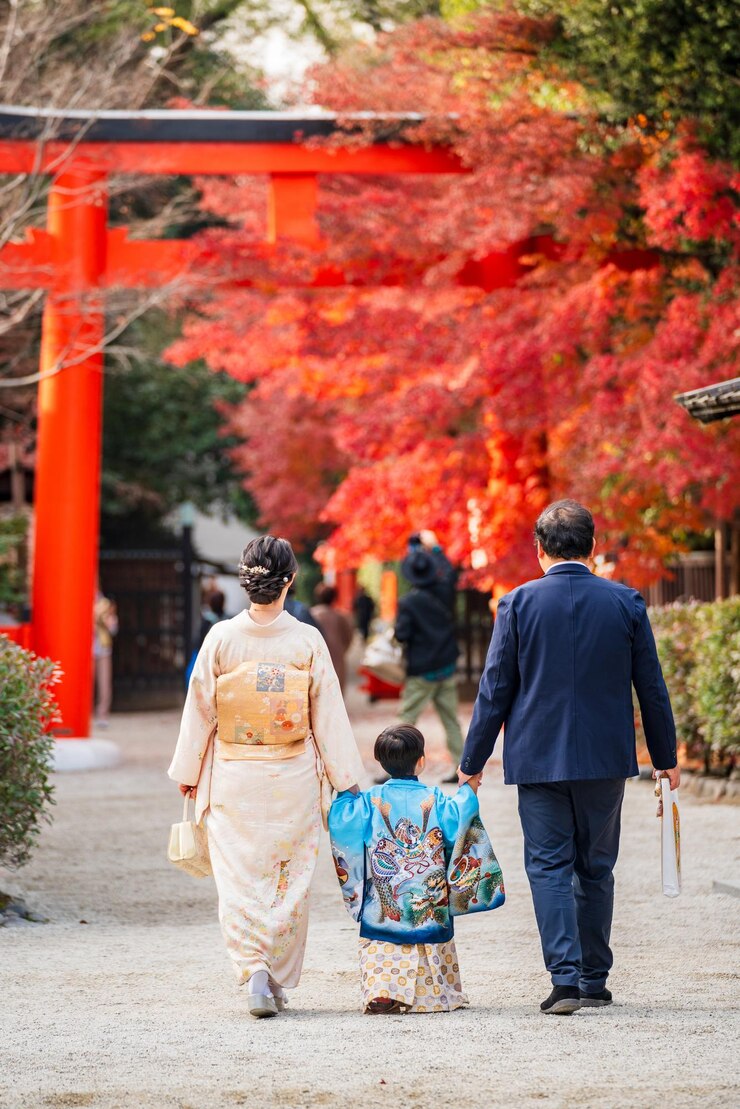 Vista de atrás de una familia vistiendo un kimono tradicional japonés en un santuario durante la temporada de arce de otoño