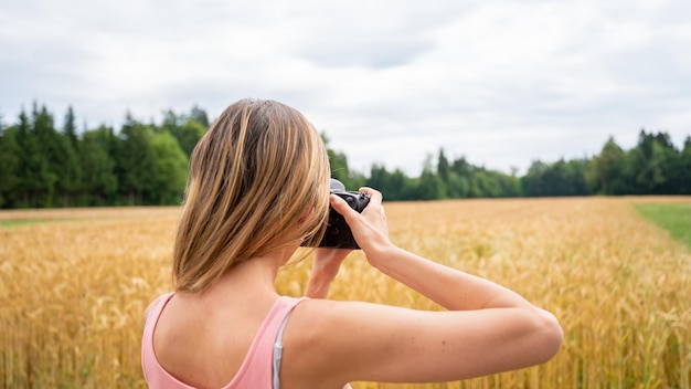 Vista desde atrás de una fotógrafa profesional tomando fotos en la naturaleza