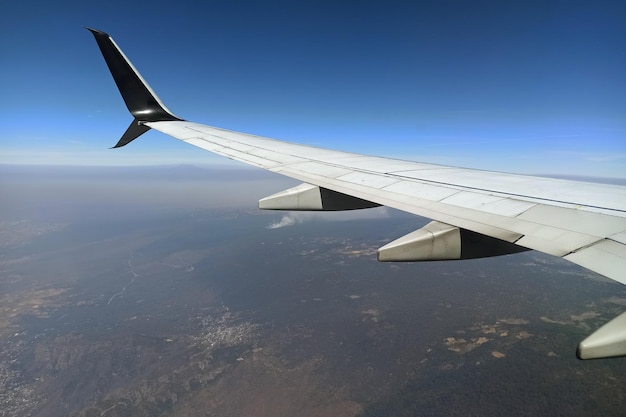 Vista através da janela do avião da asa do avião a jato comercial voando alto no céu Conceito de viagem aérea