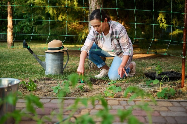 Foto vista através de uma rede para amarrar pepinos em um jovem agricultor cavando um buraco para plantar mudas em uma fazenda ecológica doméstica