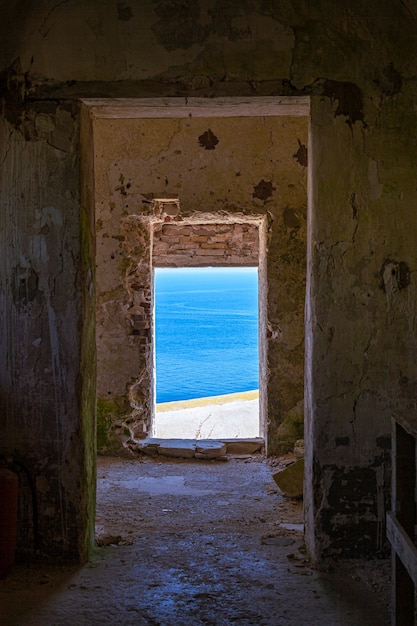 Vista através do antigo edifício em ruínas abandonado na paisagem azul do mar. Mar Adriático. Puglia, Itália.