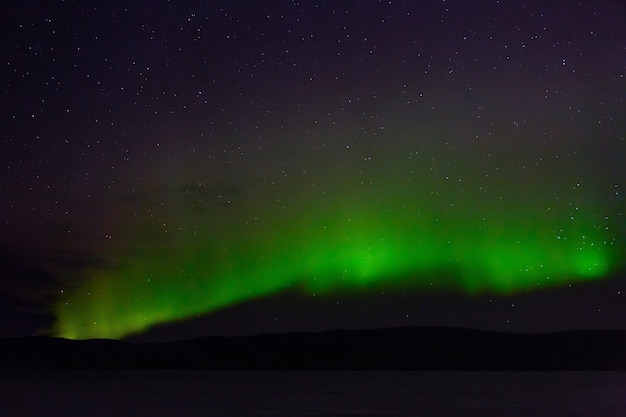 Vista de la aurora boreal. Luces polares en el cielo estrellado de la noche sobre el lago.