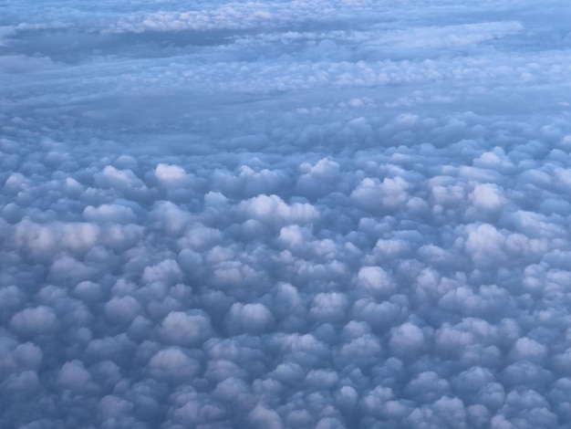 Vista desde un avión de nubes cumulus blancas en rayos de sol en el cielo azul