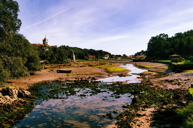 Vista de un barco naufragado en el río y la iglesia en el campo español