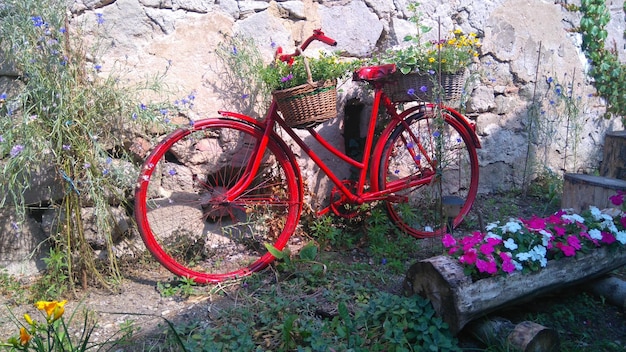 Vista de una bicicleta roja estacionada junto a una pared de piedra