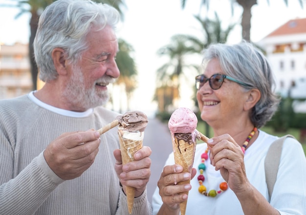 Vista borrosa de una pareja jubilada sonriente divirtiéndose comiendo helado en el parque