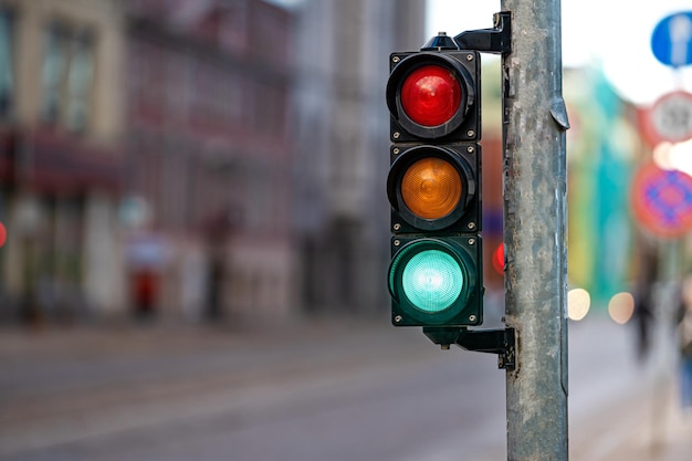 Vista borrosa del tráfico de la ciudad con semáforos en primer plano un semáforo con luz verde