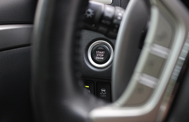 Foto vista del botón electrónico de arranque del motor a través de los radios borrosos del volante