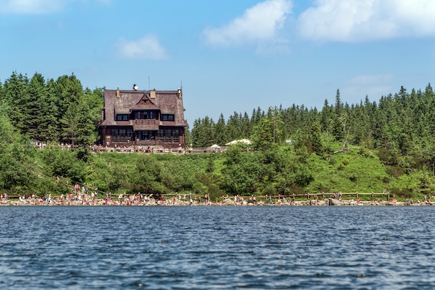 Vista de la cabaña en el lago de montaña en los Tatras con una multitud de turistas