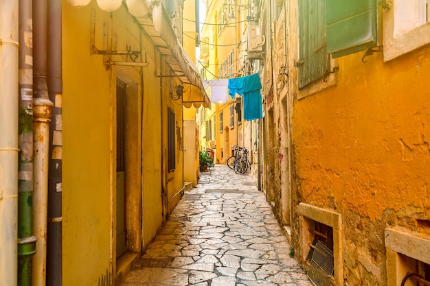 Vista de la calle angosta de la ciudad de Kerkyra con casas de colores amarillos y bicicletas durante el día soleado Isla de Corfú Mar Jónico Grecia