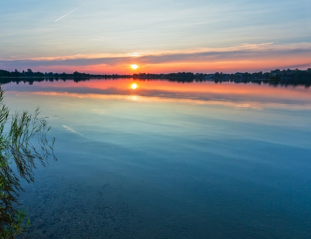 Vista calma do lago do pôr do sol de verão
