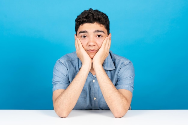 Vista de cámara web de un estudiante hispano que presta atención a la clase virtual aislada de fondo azul