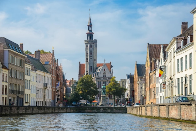 Vista desde el canal hasta la antigua iglesia catedral de casas medievales y la plaza Jan van Eyckplein en Brujas, Bélgica