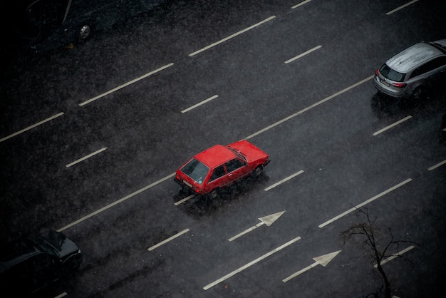 Vista del carril de la carretera de la ciudad se centró en un viejo coche rojo en un día de nieve