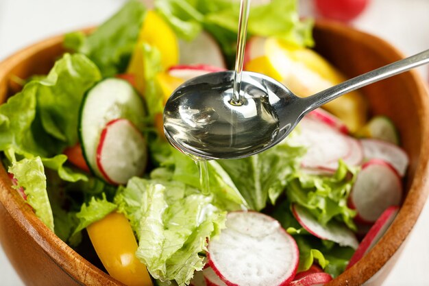 Vista de cerca del aceite que se vierte en la ensalada de verduras