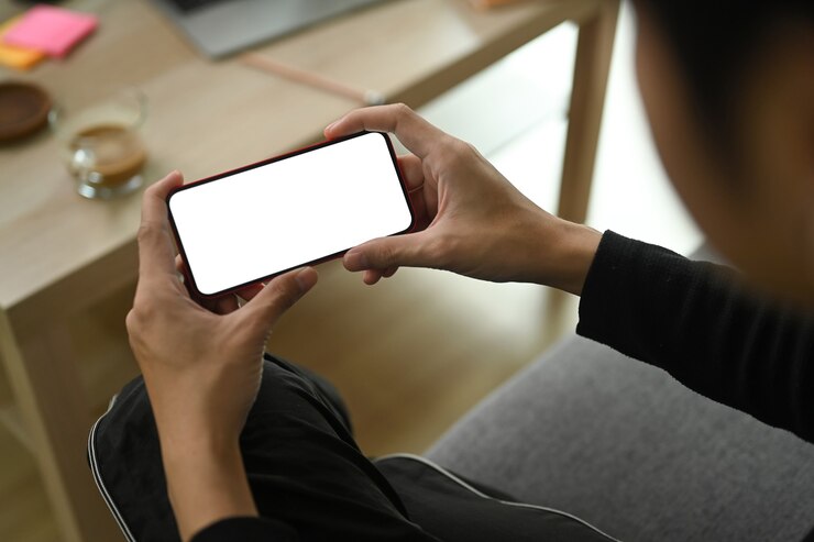 Foto vista de cerca al hombre sentado en el sofá y usando un teléfono inteligente.
