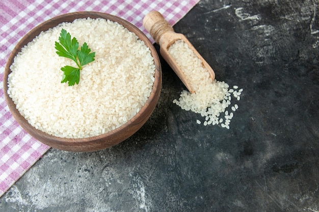 Vista de cerca del arroz redondo perfecto en un tazón marrón con verde sobre una toalla despojada de color púrpura sobre fondo de color oscuro