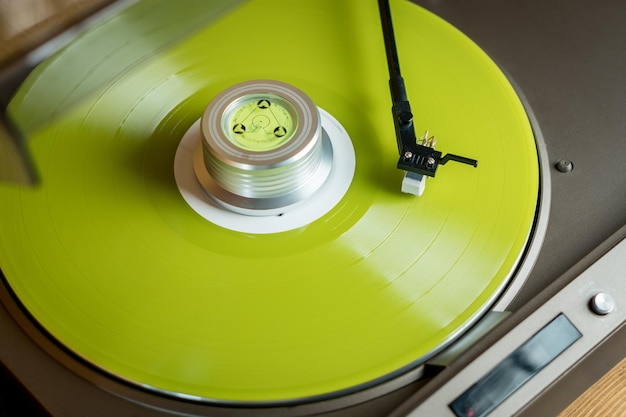 Vista de cerca de un brazo de tono y un tocadiscos tocando un disco de vinilo de color amarillo Tendencias de entretenimiento y música