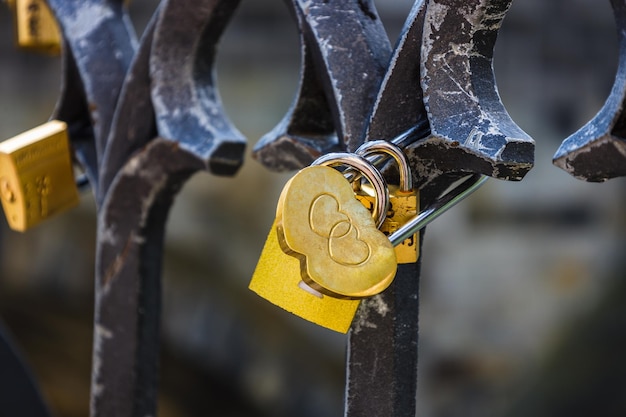 Vista de cerca del candado de amor en forma de corazón colgando de una valla de puente