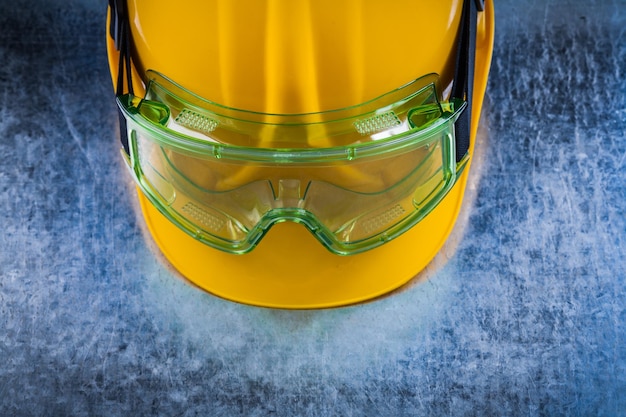Vista de cerca del casco de construcción y gafas protectoras transparentes sobre el concepto de construcción de fondo metálico rayado