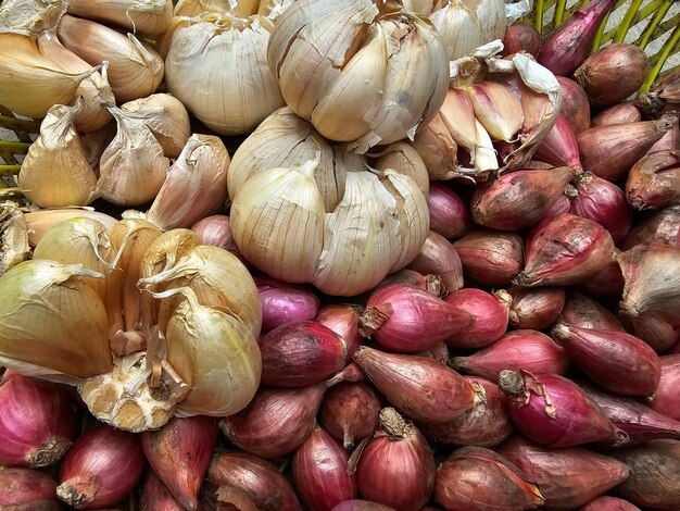 Foto vista de cerca de las cebollas rojas y el ajo en el fondo de plástico de la canasta