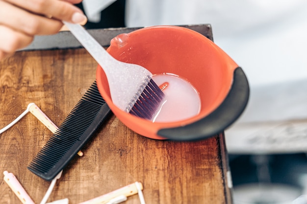 Vista de cerca de un cepillo de plástico en un recipiente de tinte para el cabello en una peluquería