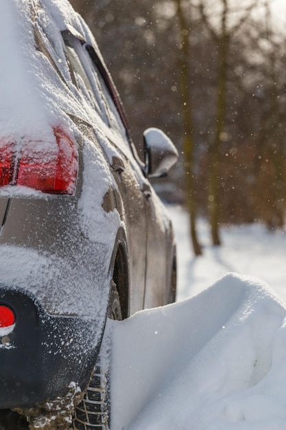 Vista de cerca del coche cubierto de nieve y deriva de nieve en su rueda