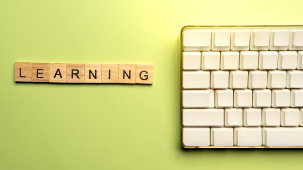 Vista de cerca de un cubo de madera con palabra de aprendizaje y teclado de computadora