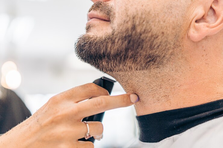 Vista de cerca del dedo de una mujer apuntando una barba afeitada de un hombre adulto caucásico en un salón
