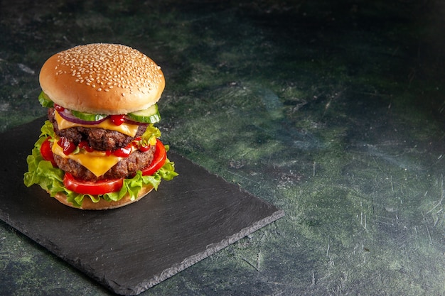 Vista de cerca del delicioso sándwich de carne con tomates verdes en la bandeja de color oscuro en el lado derecho sobre la superficie negra