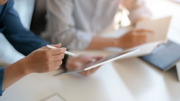 Vista de cerca de dos hombres de negocios que consultan sobre su proyecto con tableta digital y archivo de documentos