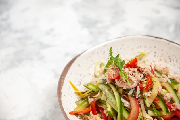 Vista de cerca de ensalada de pollo con verduras sobre una superficie blanca manchada con espacio libre