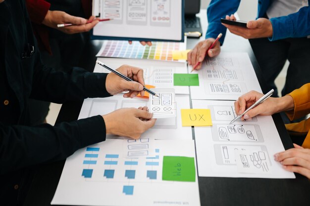 Vista de cerca del equipo de desarrolladores de la interfaz de usuario haciendo una lluvia de ideas sobre su proyecto con un teléfono inteligente portátil y una tableta digital Agencia de desarrollo digital creativaxA
