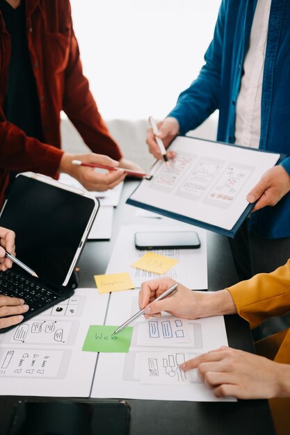 Vista de cerca del equipo de desarrolladores de UI haciendo una lluvia de ideas en su proyecto con un ordenador portátil, teléfono inteligente y tableta digital Agencia de desarrollo digital creativa con icono virtual