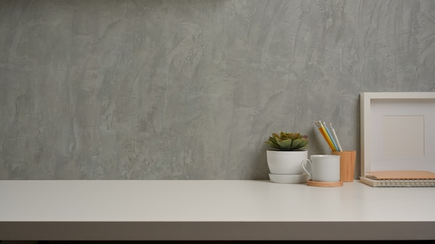 Vista de cerca del espacio de trabajo con decoraciones y copie el espacio en la mesa blanca con fondo de pared tipo loft