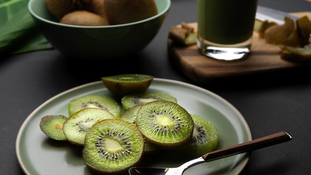 Vista de cerca de la fruta de kiwi fresca en rodajas en un plato y batido de kiwi fresco saludable en vidrio sobre la mesa de la cocina