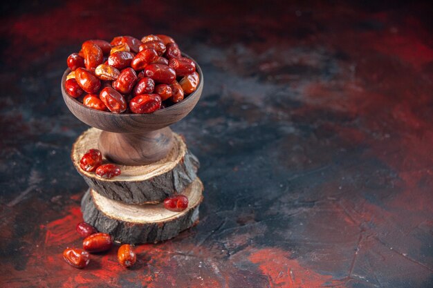 Vista de cerca de frutas de arándano crudo dentro y fuera de un recipiente sobre tablas de madera en el lado derecho sobre fondo de colores mezclados