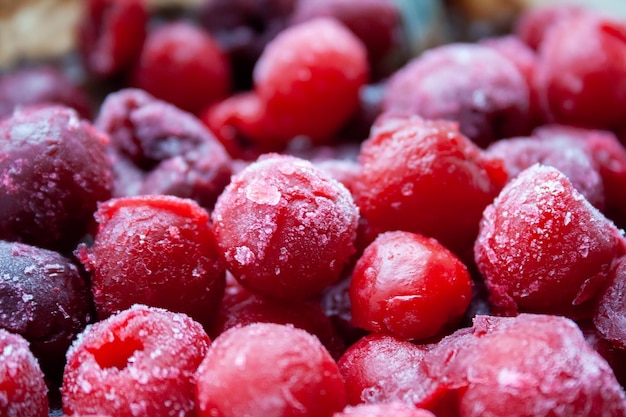 Vista de cerca de granate rojo y bayas rosadas de cerezas congeladas con escarcha