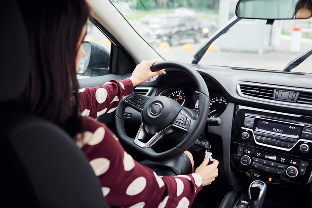 Vista de cerca de la hermosa joven morena que está dentro del automóvil moderno