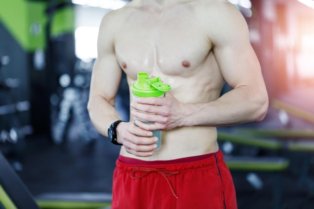 Vista de cerca del hombre musculoso en el gimnasio con abdominales en forma de agitador